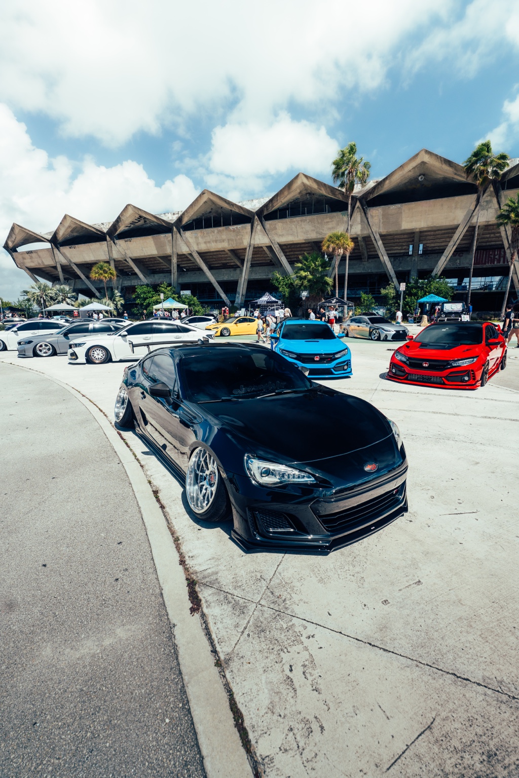 Modified cars and attendees at an ASM event outside Miami Marine Stadium